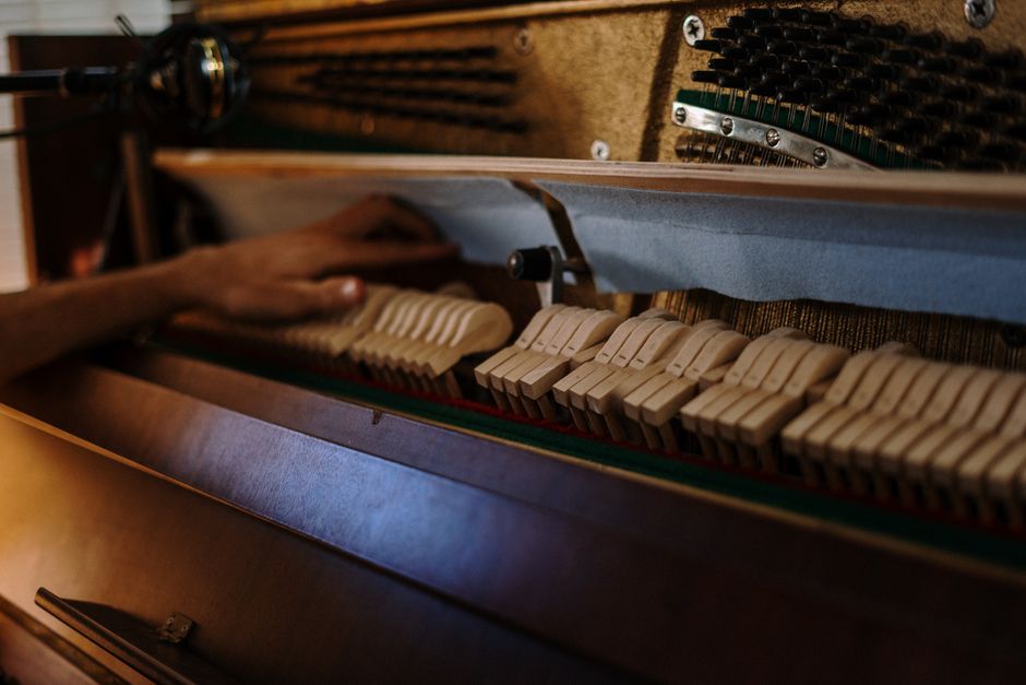 Detailed view of a piano's interior during a tuning session, showcasing strings and hammers.